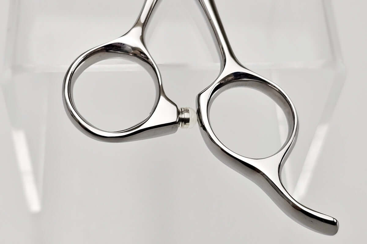 Pair of silver scissors handle on a light gray background