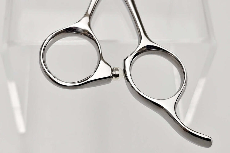 Pair of silver scissors handle on a light gray background