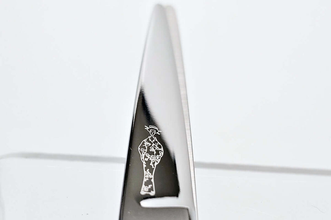 Close-up of hair scissors blade with the MICHIKO lady logo engraved on a white background