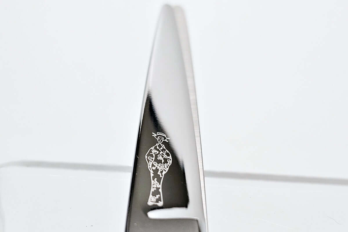 Close-up of hair scissors blade with the MICHIKO lady logo engraved on a white background