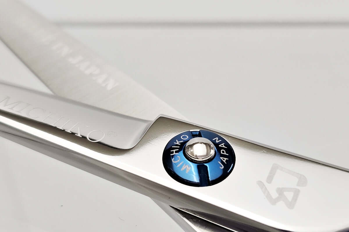 Close-up of hair scissors with a brand logo on a white background