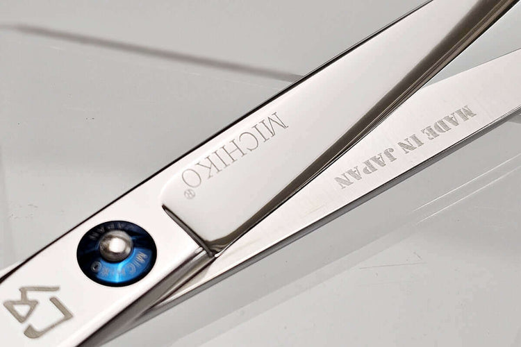 Close-up of a pair of hair scissors with 'MICHIKO' branding on a light gray background