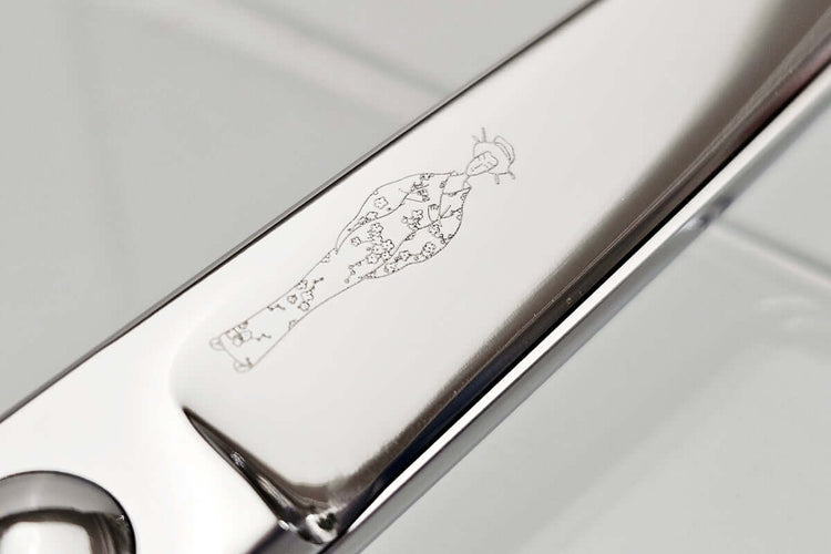 Close-up of hair scissors blade with engraved MICHIKO lady logo on a white background
