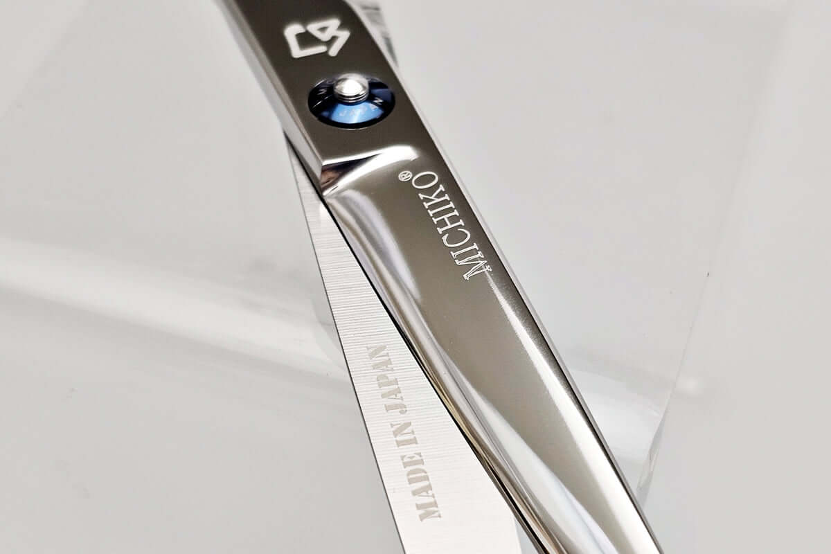 Close-up of a pair of hair scissors with 'MICHIKO' branding on a light gray background
