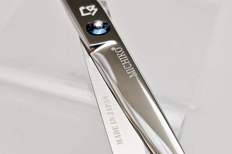 Close-up of a pair of hair scissors with 'MICHIKO' branding on a light gray background