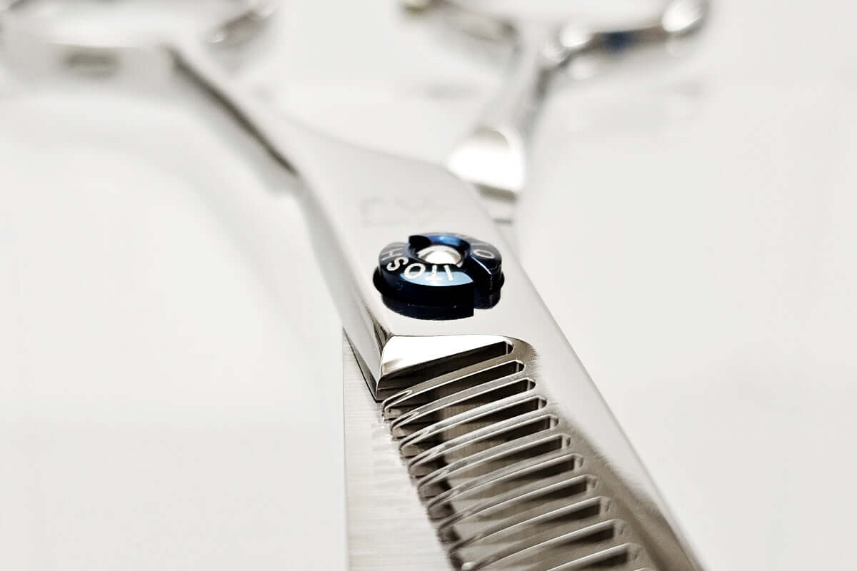 Close-up of a pair of hair thinning scissors with a brand logo on a white background