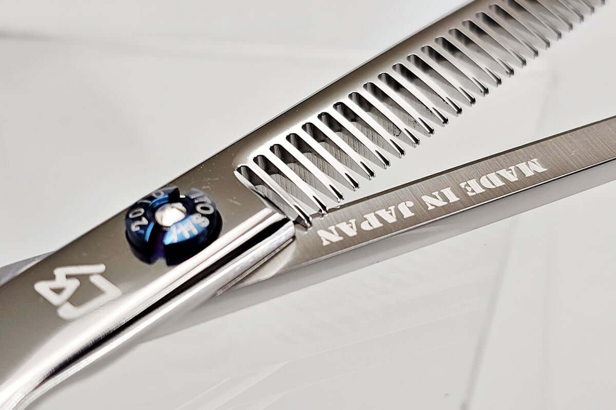 Close-up of a hair thinning scissors with 'MADE IN JAPAN' engraving on a white background